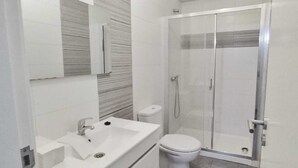 Une salle de bain moderne avec un lavabo blanc, des toilettes et une douche à parois de verre.