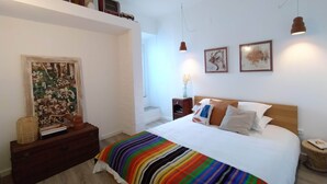 Une chambre à coucher avec un grand lit, une tête de lit en bois, une table de chevet, une commode et un tableau accroché au mur.