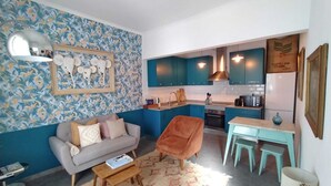 Un espace de vie compact comprenant un coin cuisine, un canapé, une table basse et un tapis à motifs.