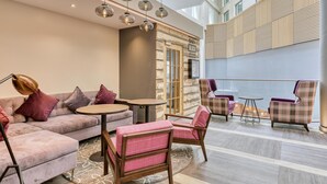 Een moderne zithoek met een bank, stoelen, een ronde tafel en een bar.