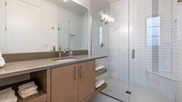 Une salle de bain moderne dotée d’un grand miroir, d’un lavabo et d’une douche à l’italienne.