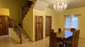 Un espace repas agrémenté d’un lustre, d’un escalier en bois et d’une table à manger avec des chaises.