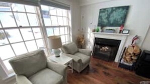 A living room with a fireplace, a sofa, and a coffee table. - Deluxe 2xQueen & fireplace (Dover)