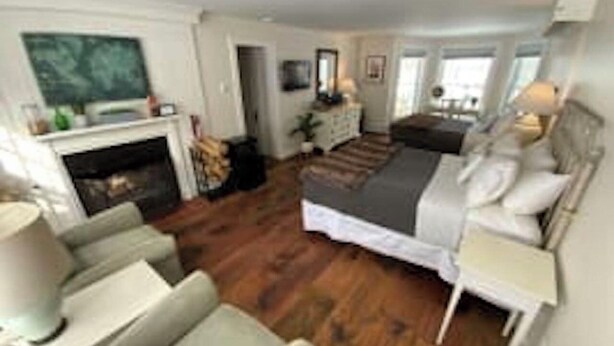 A modern bedroom with a bed, bedside tables, a dresser, and a fireplace. - Deluxe 2xQueen & fireplace (Dover)