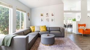 Una sala de estar moderna con un sofá seccional gris, una mesa de centro redonda y una alfombra estampada.