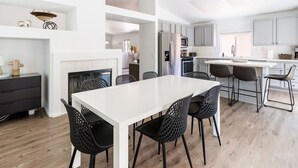Una cocina moderna con armarios blancos, una isla central y sillas negras.