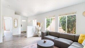 Una sala de estar moderna con un sofá modular, una mesa de centro redonda y un gran ventanal con vistas a la vegetación.