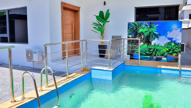 A swimming pool with metal railings, a wooden door, and a large potted plant. - LAS VEGAS NEVADA @ AMERICA LUXURY EXTENDED STAY (Lagos)