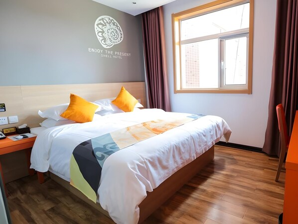 Una habitación de hotel con cama, mesita de noche, ventana con cortinas y una pared con un logotipo y texto.