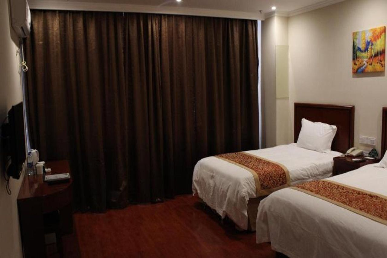 A hotel room with two beds, a desk, a telephone, and a painting on the wall.