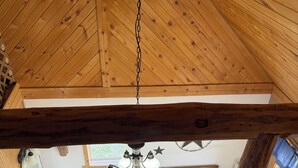L’intérieur d’un chalet rustique, avec un plafond en bois, un luminaire suspendu, un évier et un tapis orné de motifs en forme d’étoiles.