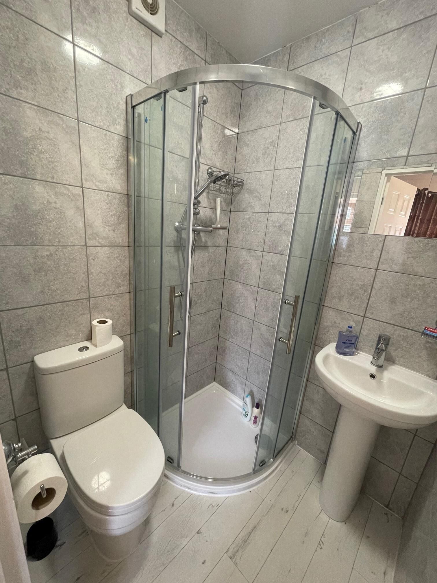 A bathroom with a glass-enclosed shower, a toilet, and a sink.