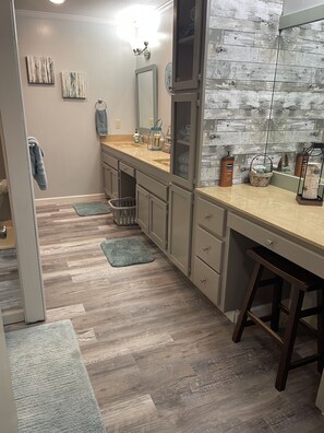 A modern bathroom with wooden flooring, a beige countertop, a sink, a mirror, and a towel rack. - Relax on the edge of Little Red @ Griffin Little Red River Cabin (Heber Springs)