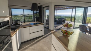 A modern kitchen with large windows, a dining area with a view, and a fruit bowl on the counter. - Villa with private Jacuzzi, relaxing wellness weekends and holidays, seaside (Plougonvelin)