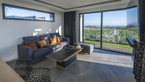 A modern living room with a grey sofa, a coffee table, and a view of a green landscape through large windows. - Villa with private Jacuzzi, relaxing wellness weekends and holidays, seaside (Plougonvelin)