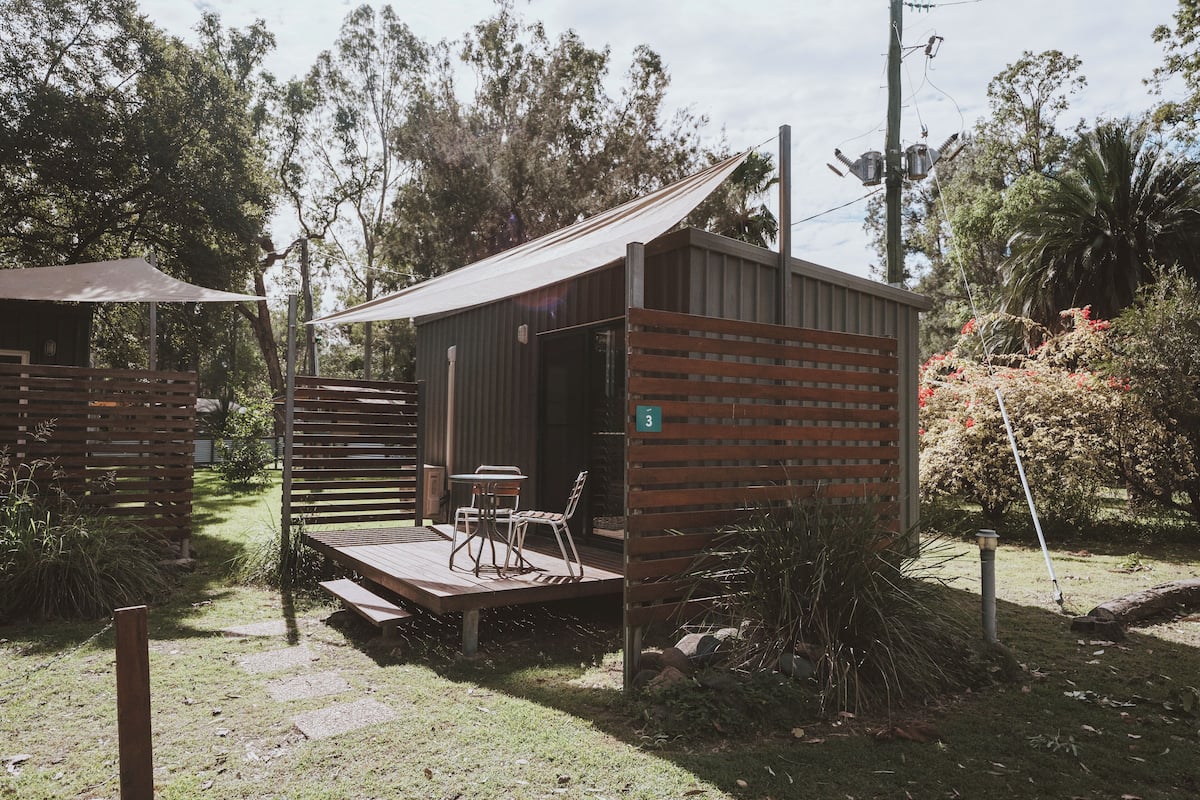 A small, single-room structure with a wooden deck and a table with chairs.