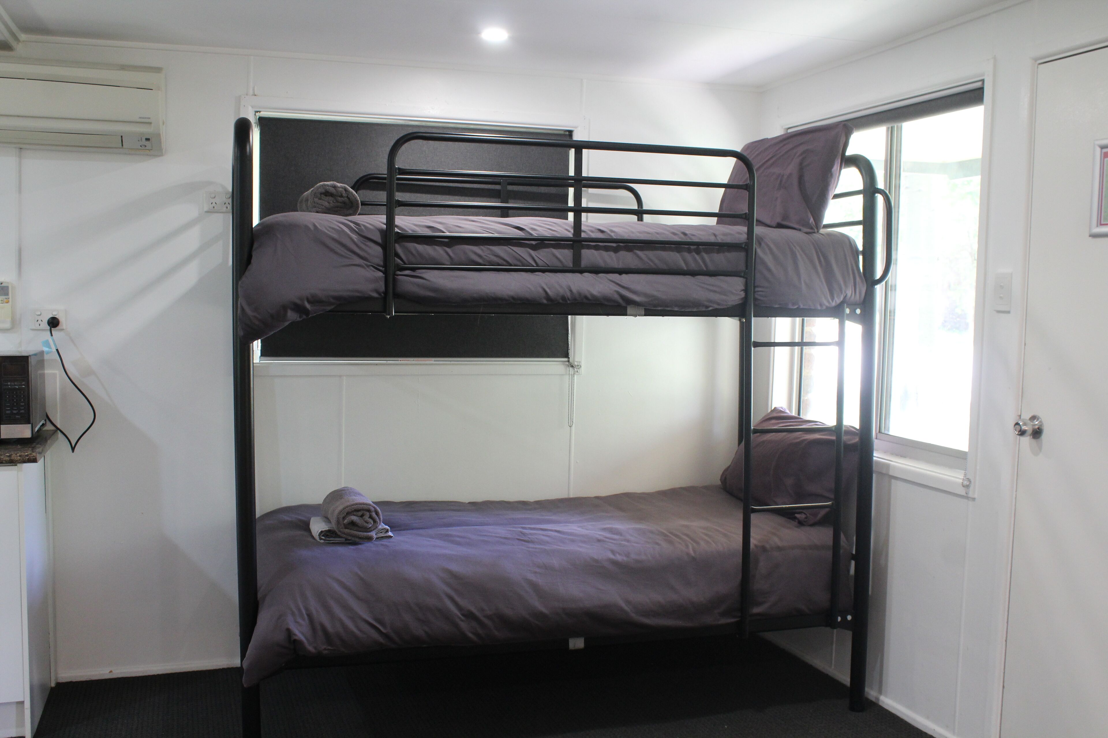 A bunk bed room with a window, a door, and a small desk with a computer.