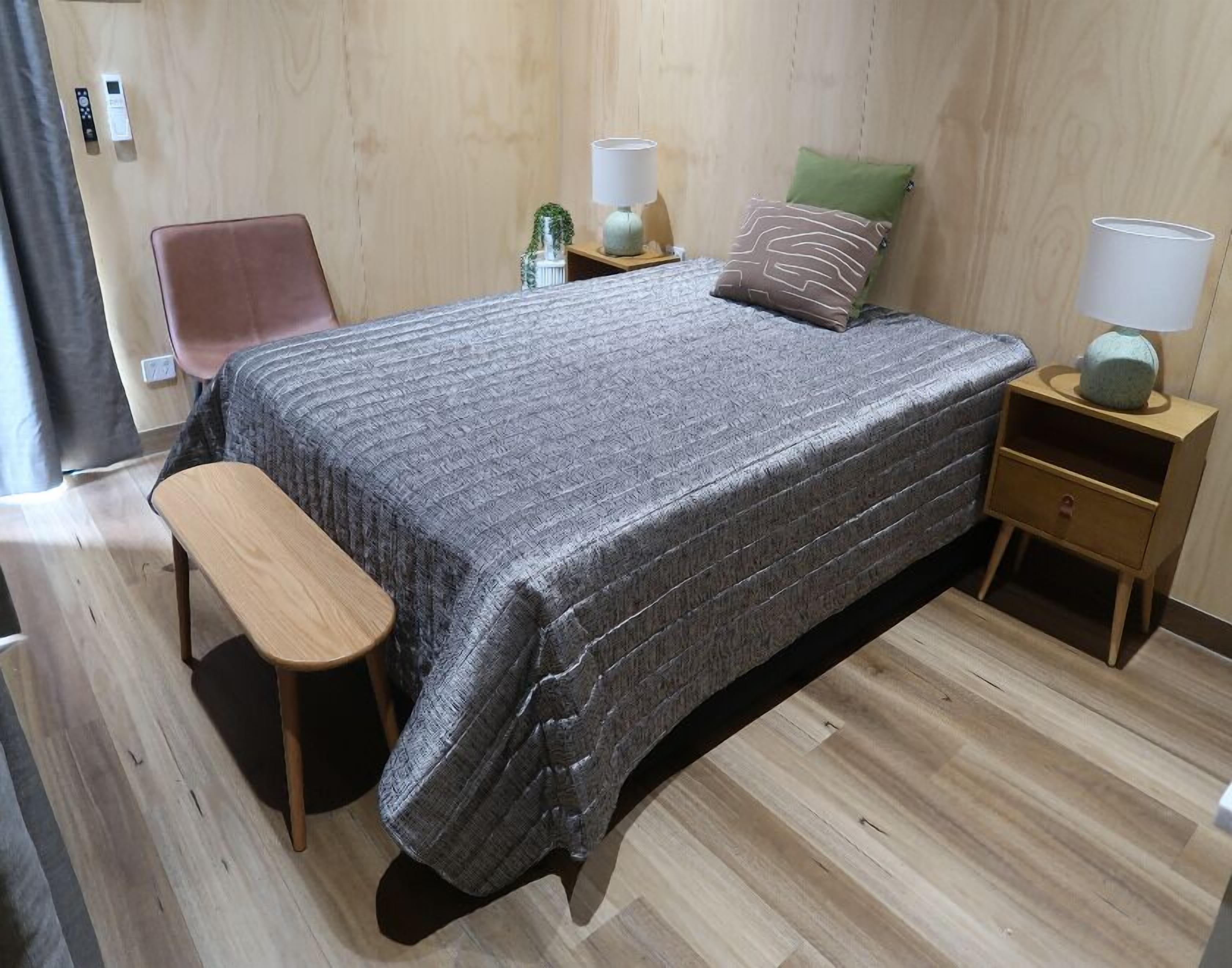 A bedroom with a bed, bedside tables, a bench, and a chair.