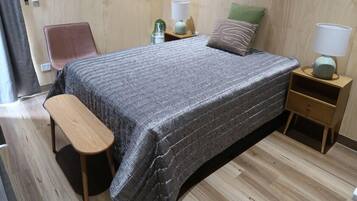 A bedroom with a bed, bedside tables, a bench, and a chair.