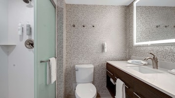 A modern bathroom with a glass-enclosed shower, a white toilet, and a wooden vanity with a sink.