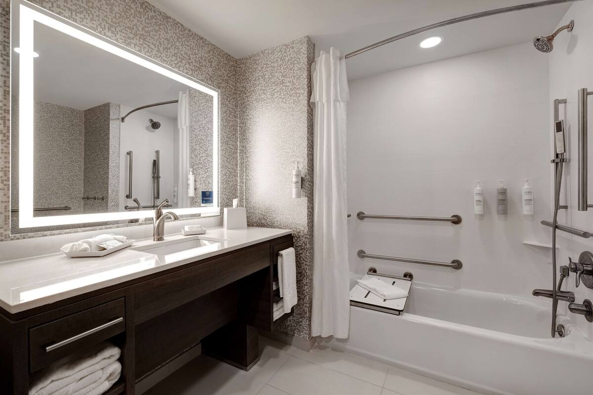 A modern bathroom with a large mirror, a bathtub, and a shower.