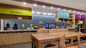 A modern restaurant with a wooden dining area, a counter with kitchen appliances, and a sign that reads "GOOD MORNING". - Home2 Suites by Hilton Wilkes-Barre (Wilkes-Barre)