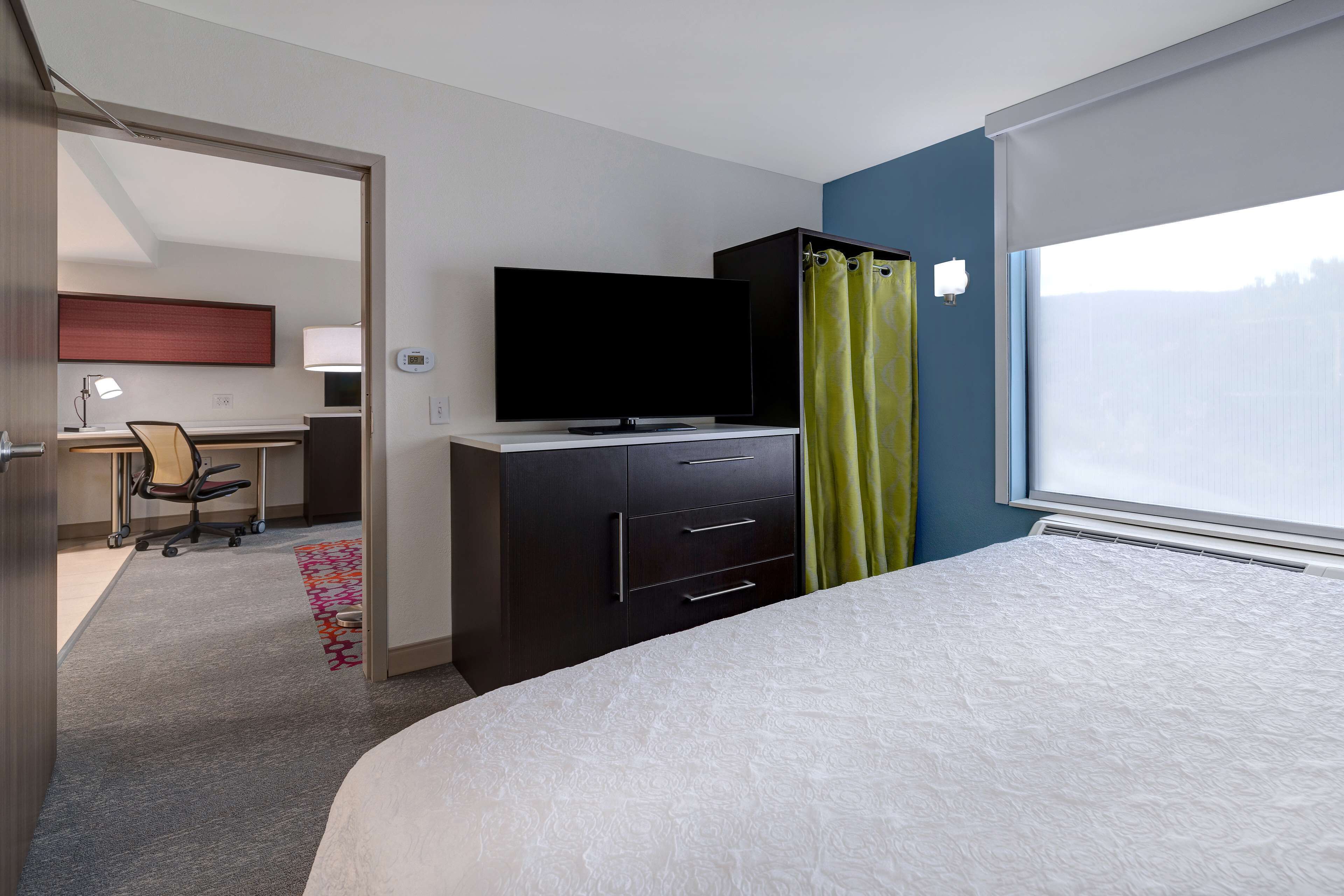 Habitació d'hotel amb llit, televisió, escriptori amb cadira i finestra amb vista.
