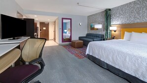 A hotel room with a bed, a desk with a computer, a chair, a sofa, and a television. - Home2 Suites by Hilton Wilkes-Barre (Wilkes-Barre)