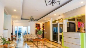 A hotel lobby with a checkered floor, a reception desk, a sofa, and a chandelier. - Hotel Utari Dago (Bandung)