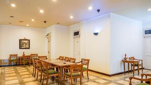 A dining area with a checkered floor, wooden tables, and chairs. - Hotel Utari Dago (Bandung)