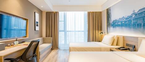 Habitación de hotel con un ventanal grande, un escritorio con computadora, una cama y un televisor instalado en la pared.