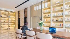 A modern library with bookshelves, a wooden table, and a laptop. - Atour Hotel (Jiaxing)