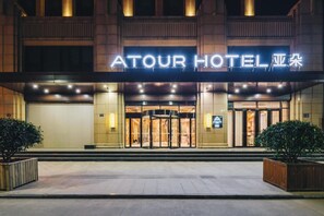 A hotel entrance with a revolving door and a sign reading "ATOUR HOTEL".
