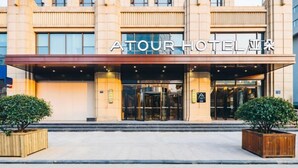 A hotel entrance with a modern facade, glass doors, and a sign reading "ATOUR HOTEL". - Atour Hotel (Jiaxing)