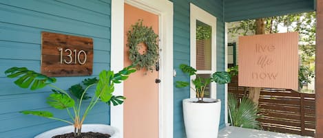A house with a number sign '1310', a door with a wreath, and a sign saying 'live life now'.