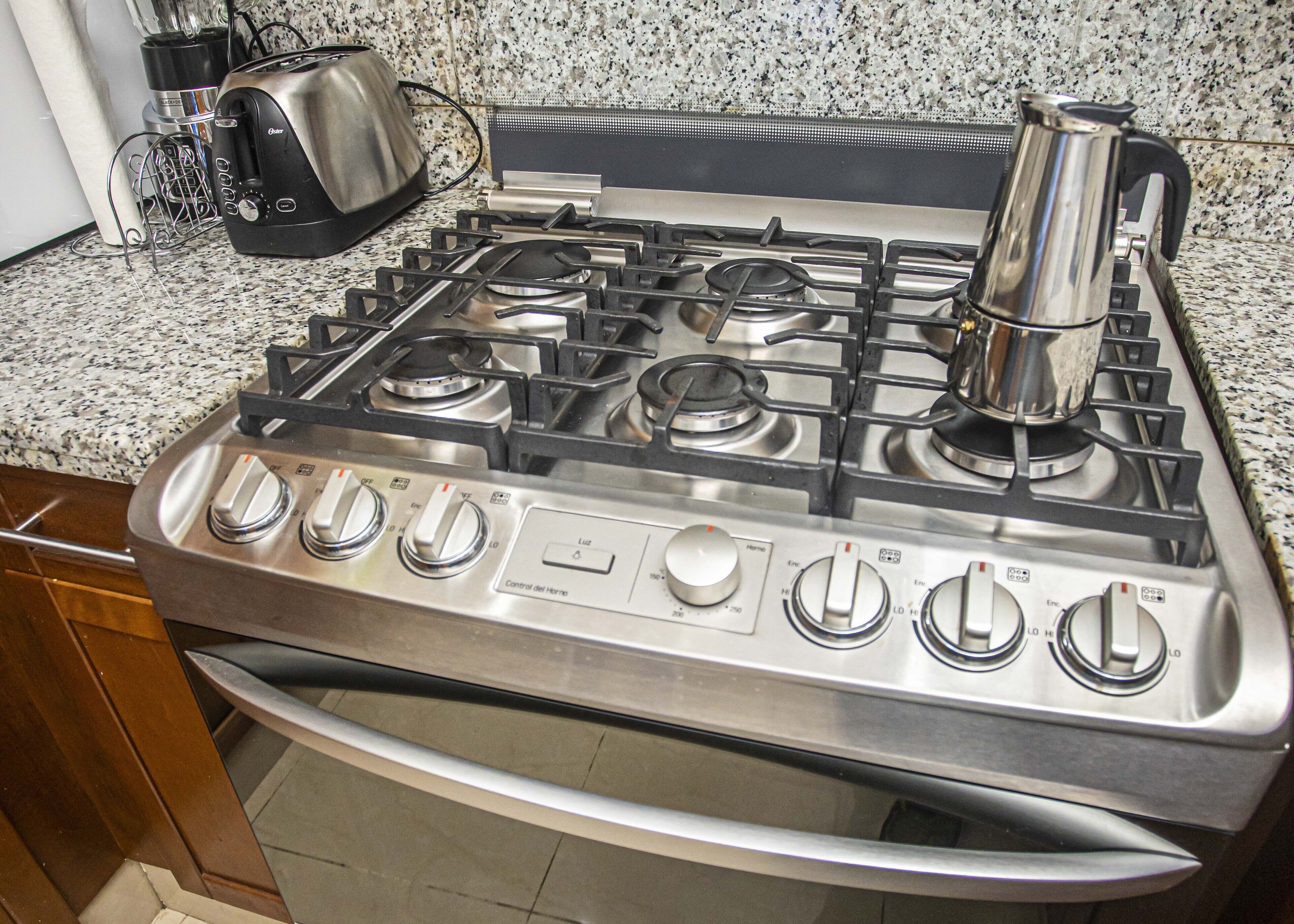 A kitchen with a stainless steel gas stove, a toaster, and a kettle.