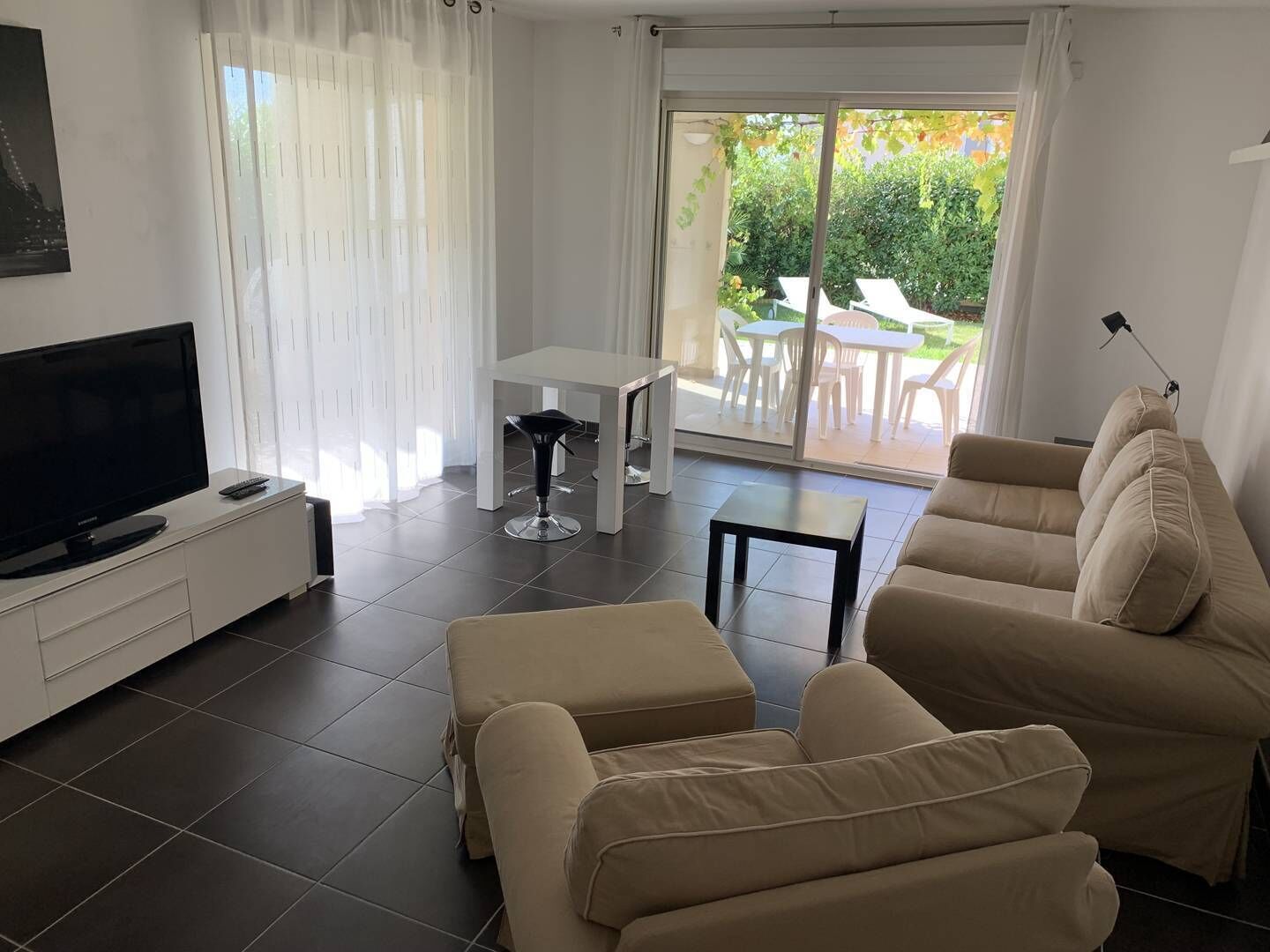 Een moderne woonkamer met een flatscreen televisie, een bank, een salontafel en een eethoek met een tafel en stoelen.