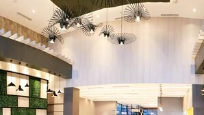 Um hall amplo com design moderno, apresentando uma escadaria, áreas de estar e um balcão de recepção.