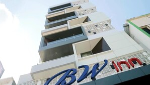 Um edifício de hotel com vários andares e uma placa de destaque que diz 'BW Inn'.