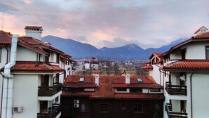 Zona residencial con edificios que tienen tejados rojos y balcones, con montañas al fondo.