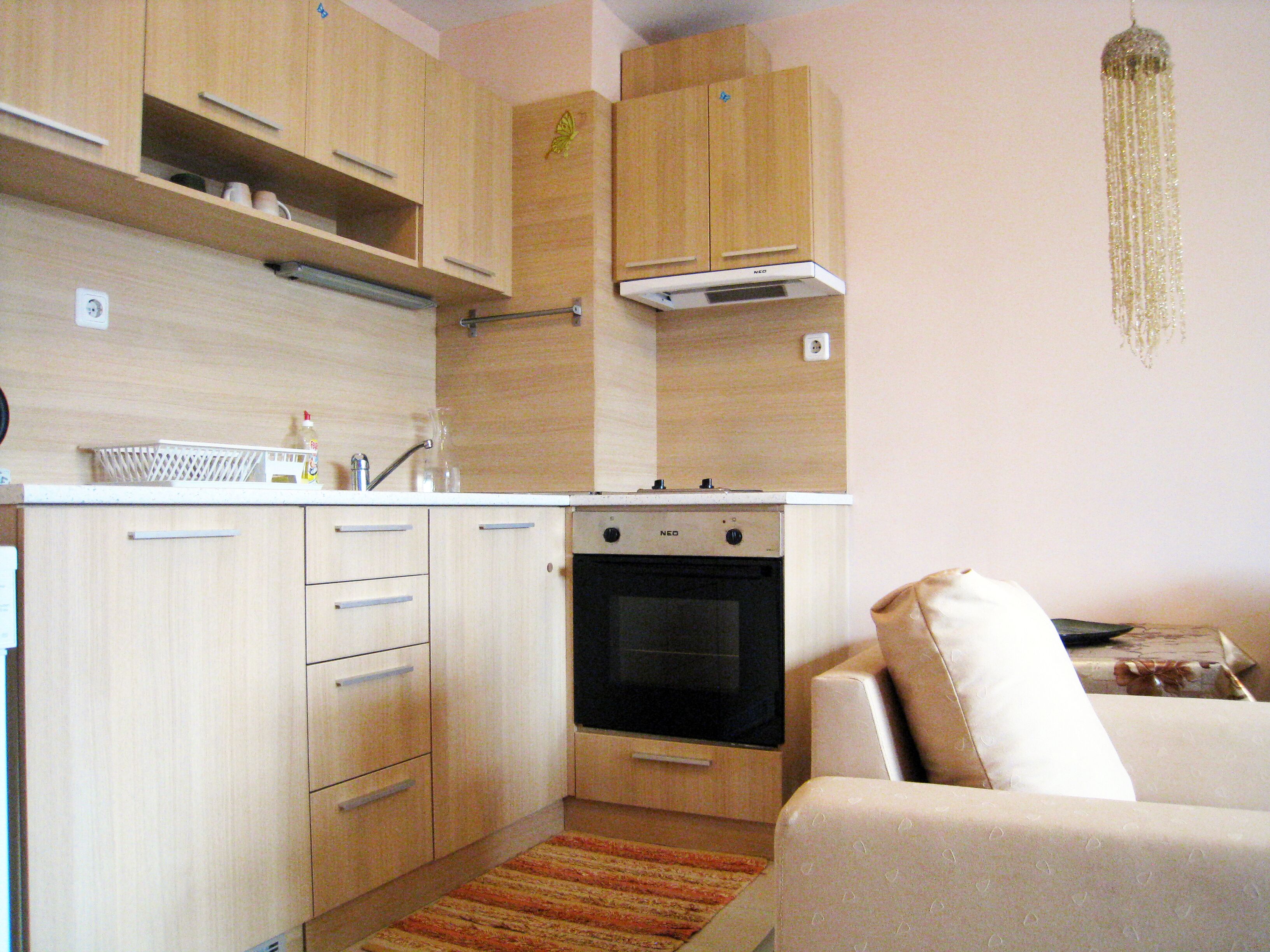 A compact kitchen with wooden cabinets, a built-in oven, and a white countertop.
