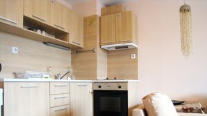 Una cocina compacta con armarios de madera, horno empotrado y encimera blanca.