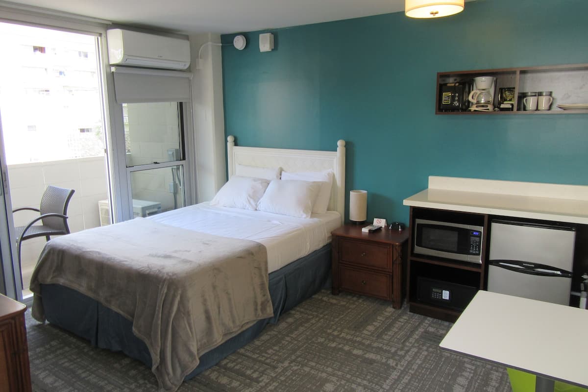 Una habitación de hotel con una cama, un escritorio, microondas y cafetera.