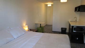 A hotel room with a bed, a desk, a microwave, and a small sink.