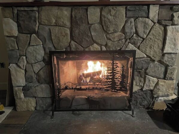 A stone fireplace with a fire burning inside, surrounded by a stone wall.