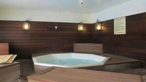 A spa area with a hot tub, wooden panel walls, and wall-mounted lights.
