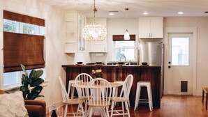 A modern kitchen with white cabinetry, a central island, and a dining area with white chairs. - Outdoor Oasis in Historic St. Augustine (Saint Augustine)
