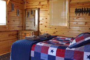Une chambre dans un chalet en bois, avec un lit, une commode et une fenêtre équipée de stores.