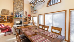 Un vaste espace dédié à la salle à manger, avec une longue table en bois entourée de chaises, et un mur décoratif en pierre.