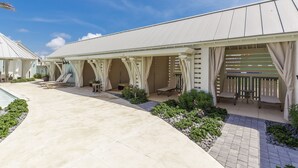 A covered outdoor area with lounge chairs and a pool. - Designer Condo in Popular Palmilla | Close to Pool & Boardwalk (Port Aransas)